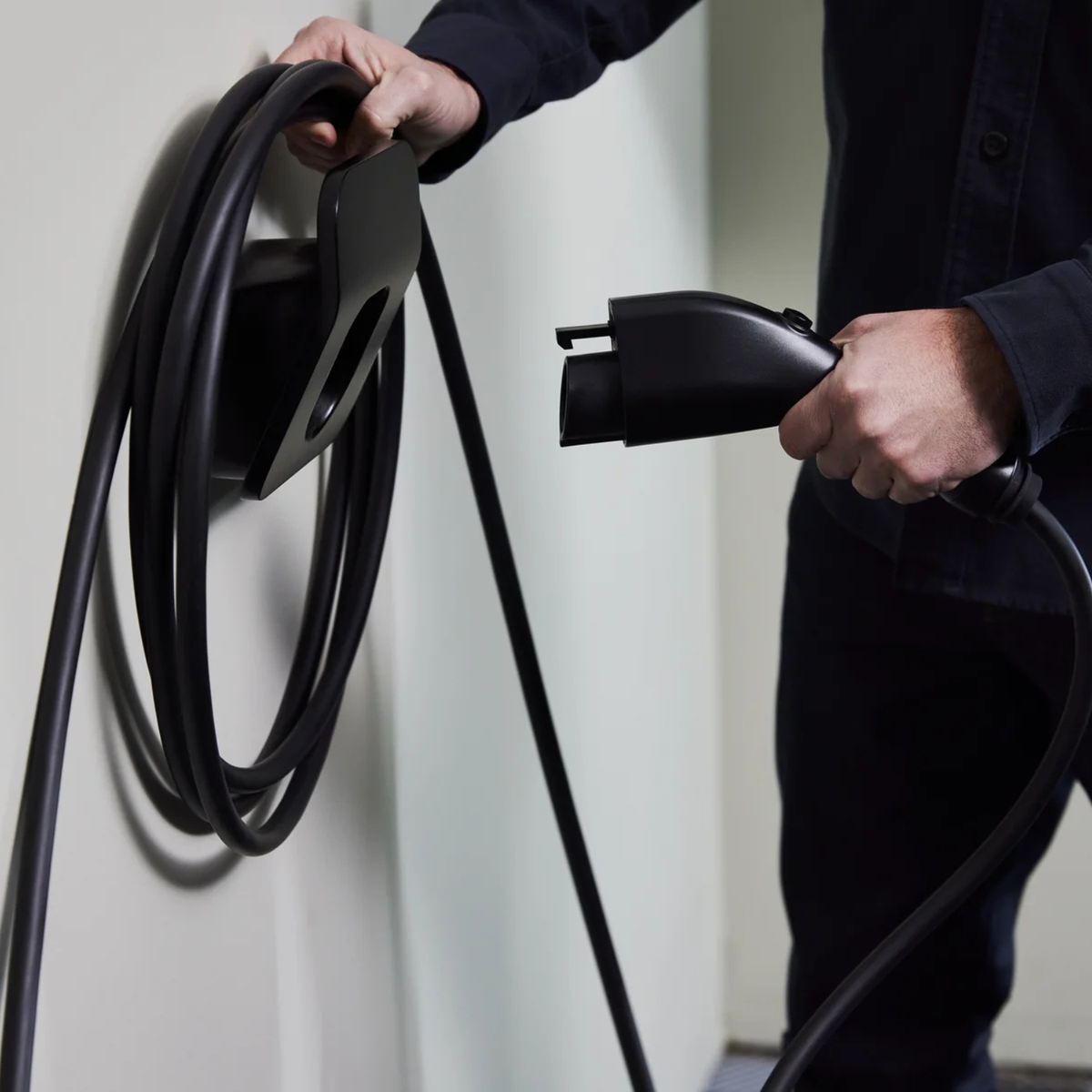 Support câble EV FLO installé au mur, près d'une borne de recharge